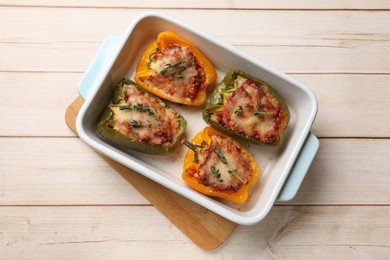 Photo of Tasty stuffed peppers in dish on wooden table, top view