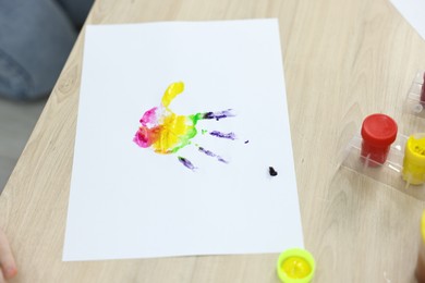 Photo of Cute child's handprint and different paints on wooden table