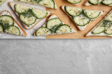 Tasty sandwiches with cream cheese, cucumber and dill on grey marble table, flat lay. Space for text