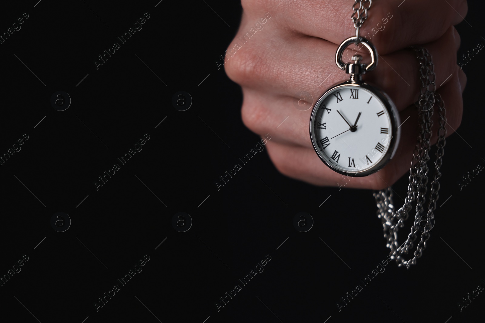 Photo of Man holding chain with elegant pocket watch on black background, closeup. Space for text