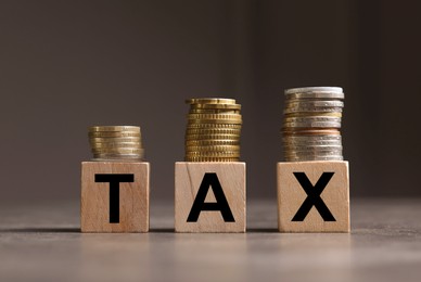 Word Tax made of wooden letters and coins on grey table, space for text