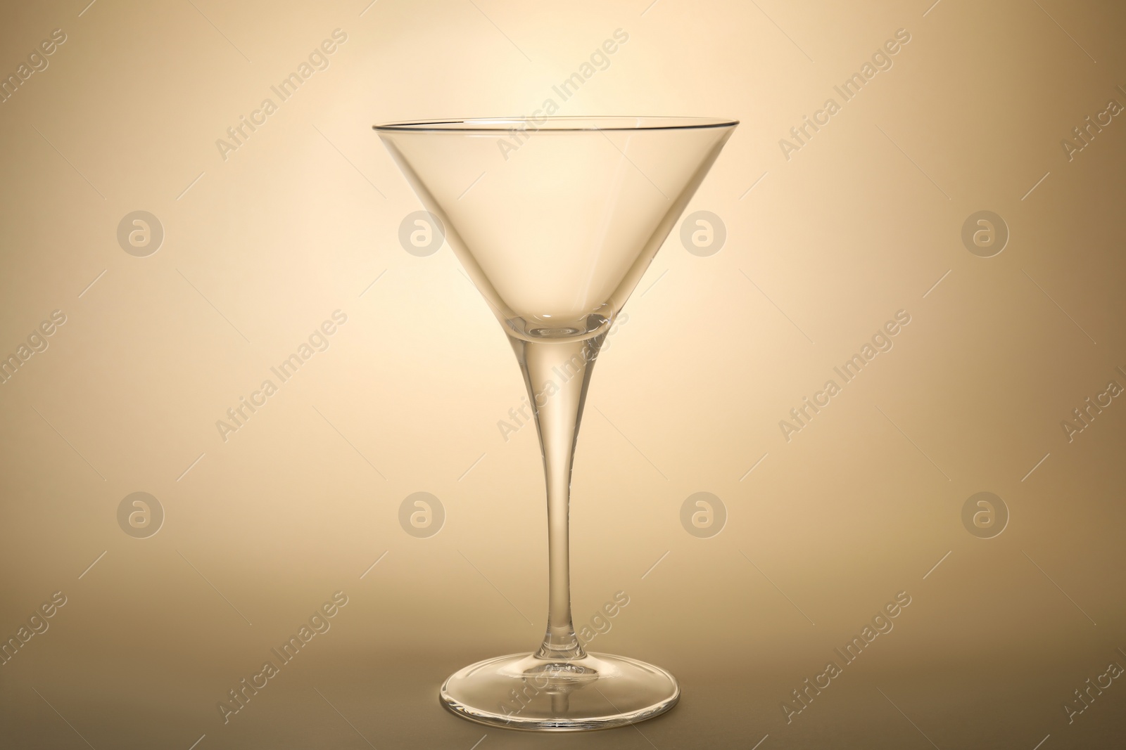 Photo of Elegant empty martini glass on beige background