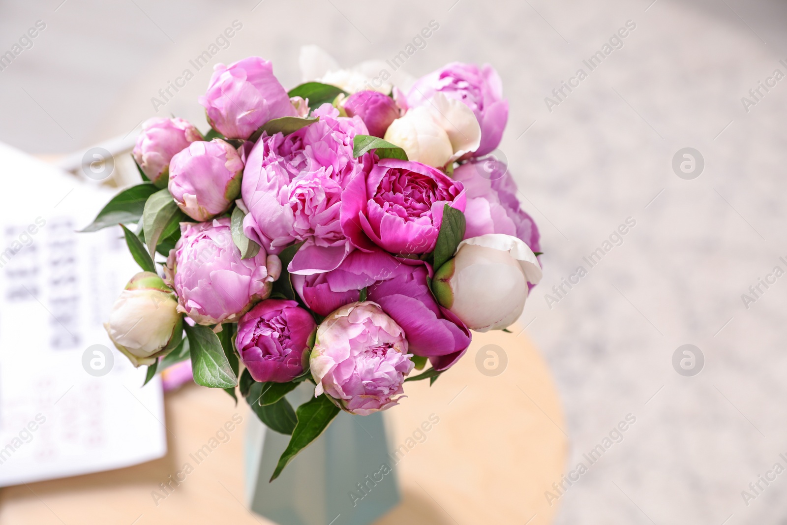 Photo of Vase with bouquet of beautiful peonies on table in room, above view. Space for text