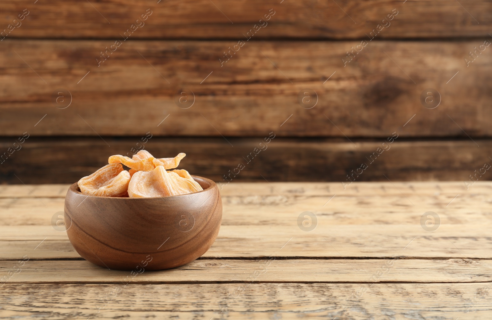 Photo of Delicious dried jackfruit slices in bowl on wooden table. Space for text