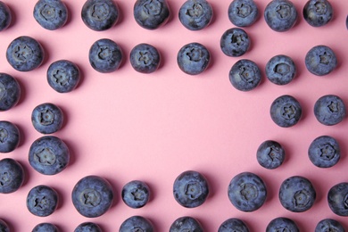 Photo of Frame of ripe blueberries on pink background, flat lay with space for text