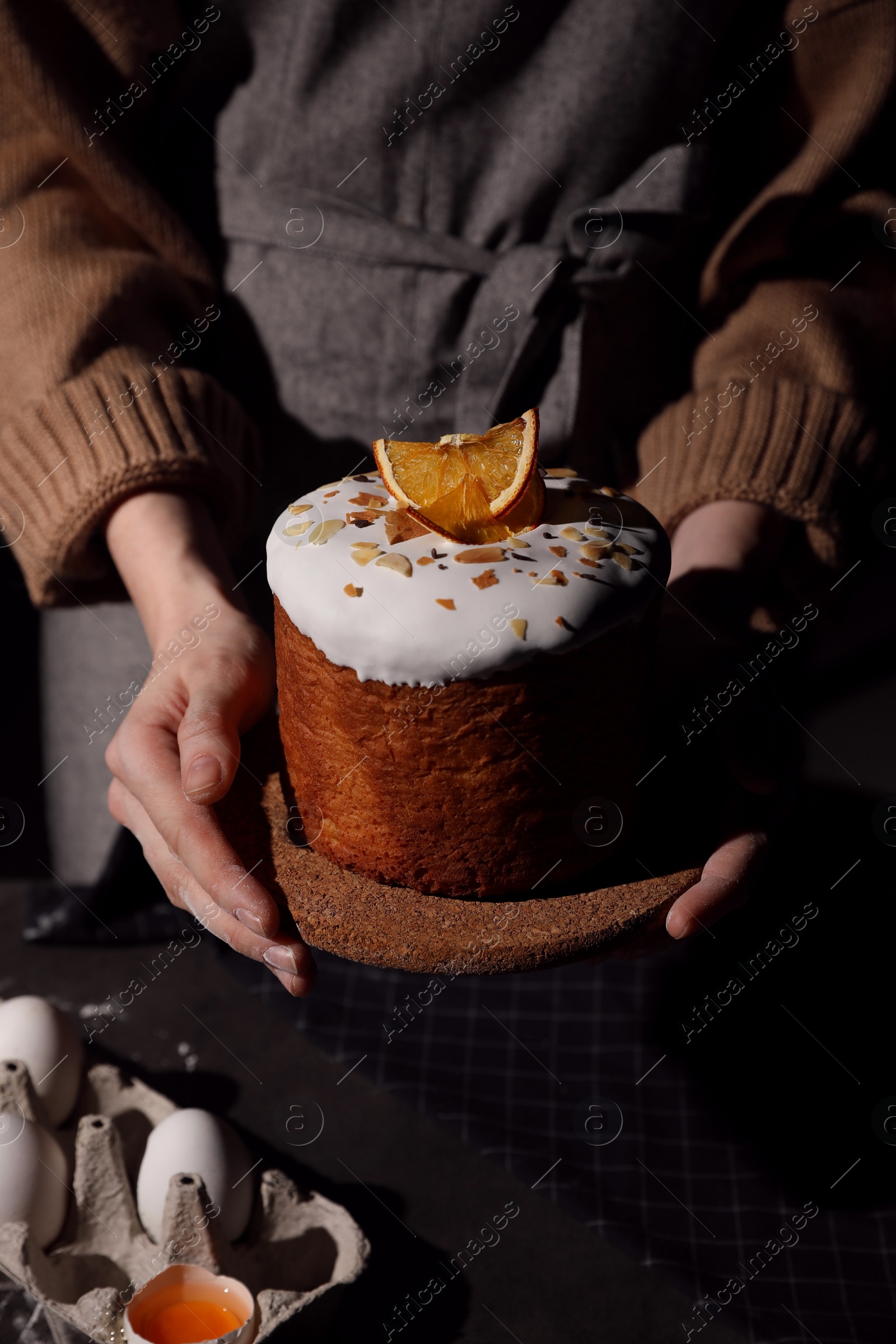 Photo of Young woman holding traditional decorated Easter cake over table, closeup