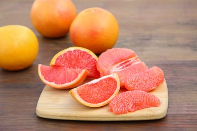 Photo of Cut and whole fresh ripe grapefruits on wooden table