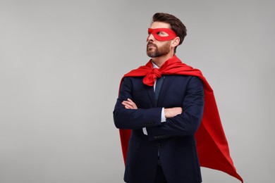 Photo of Confident businessman wearing red superhero cape and mask on beige background. Space for text