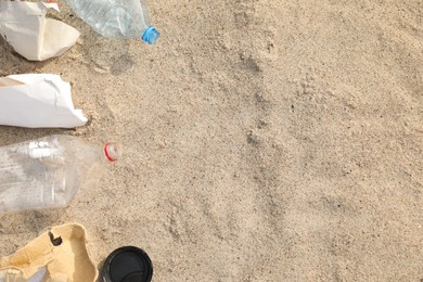 Photo of Garbage scattered on sand, flat lay with space for text. Recycling problem