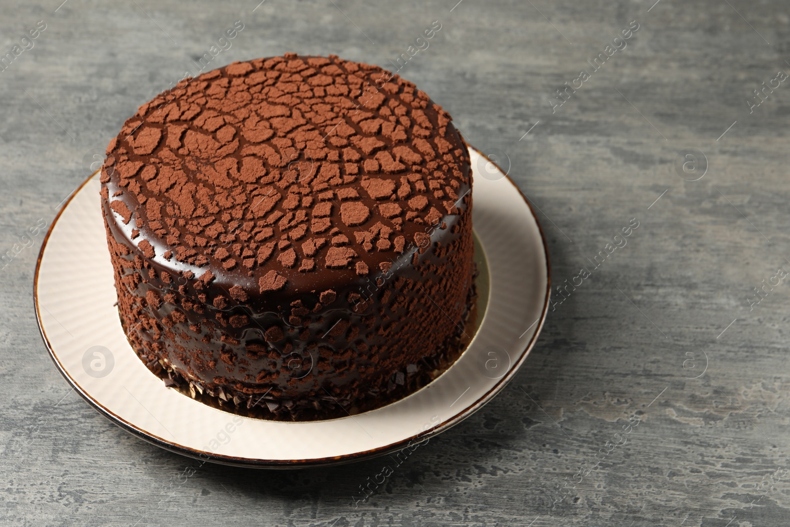 Photo of Delicious chocolate truffle cake on grey textured table, space for text