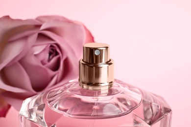 Photo of Bottle of perfume and blurred rose on background, closeup