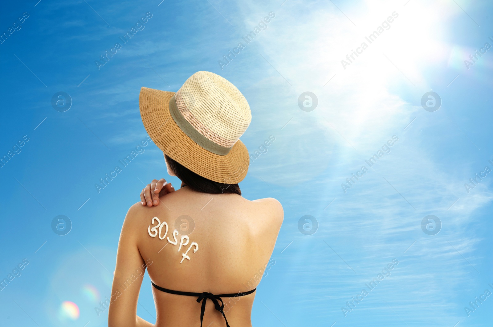 Image of Young woman with sun protection cream on her back outdoors