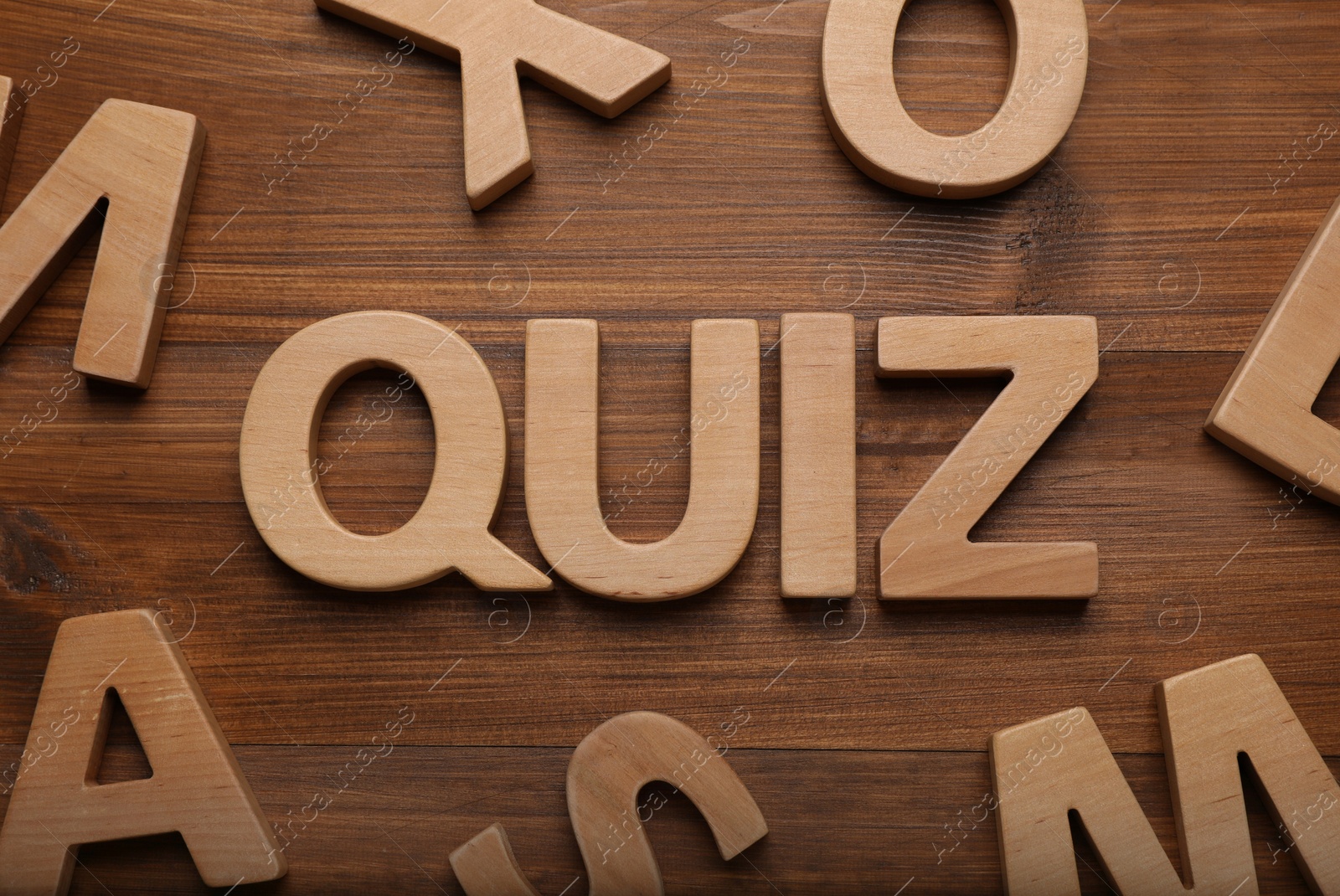 Photo of Word Quiz made with letters on wooden table, flat lay