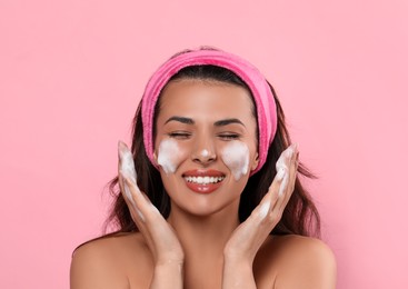 Photo of Beautiful woman applying facial cleansing foam on pink background