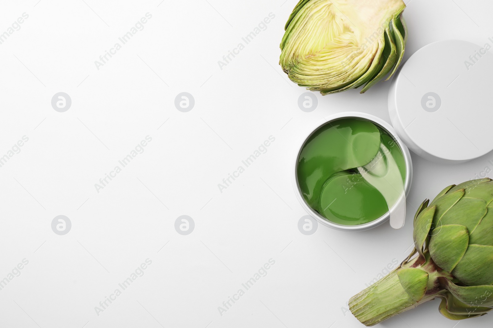 Photo of Package of under eye patches and artichokes on white background, top view. Cosmetic product