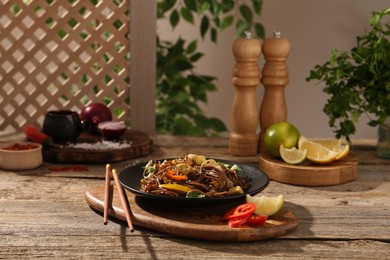 Photo of Stir-fry. Tasty noodles with meat and vegetables served on wooden table