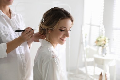 Professional stylist making wedding hairstyle for bride in salon