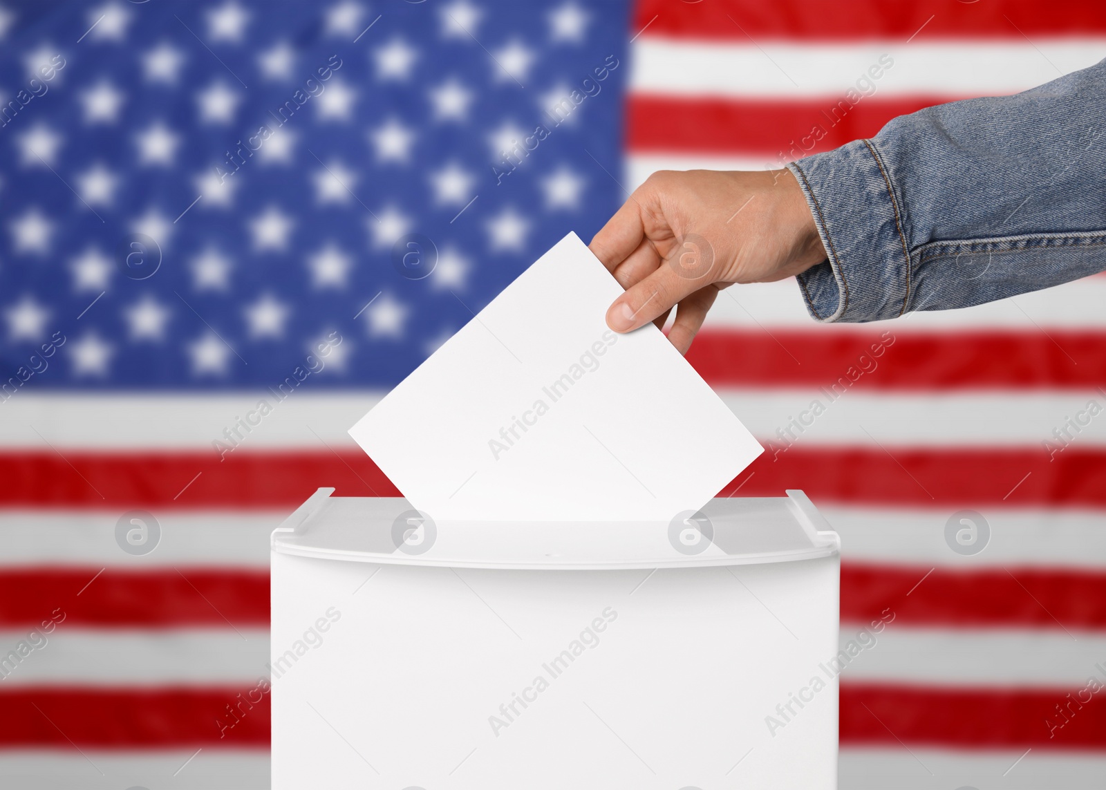 Image of Election in USA. Man putting his vote into ballot box against national flag of United States, closeup