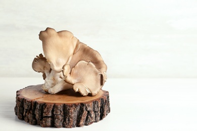 Wooden coaster with delicious organic oyster mushrooms on table, space for text