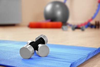 Photo of Dumbbells on yoga mat indoors, closeup. Physiotherapy center