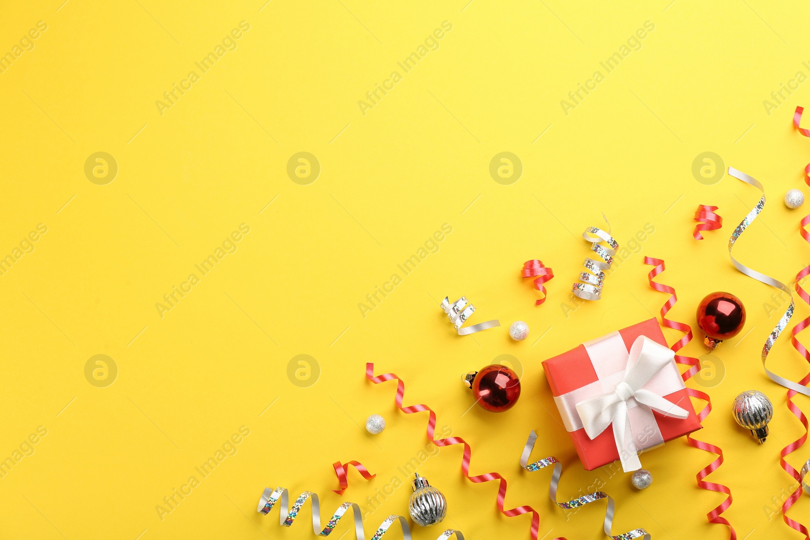 Photo of Flat lay composition with serpentine streamers and Christmas decor on yellow background. Space for text