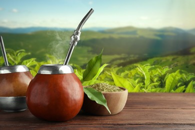 Calabashes with mate tea and bombilla on wooden table. Space for text