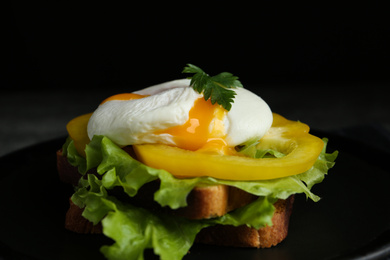 Delicious poached egg sandwich served on black plate, closeup