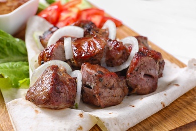 Wooden board with juicy shish kebab, closeup