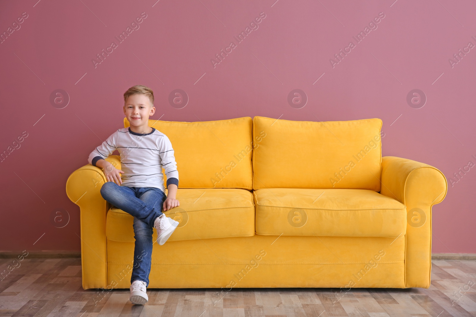 Photo of Cute little boy sitting on sofa, indoors