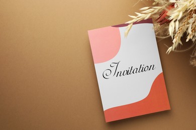 Photo of Beautiful card with word Invitation and dry flowers on beige background, top view. Space for text