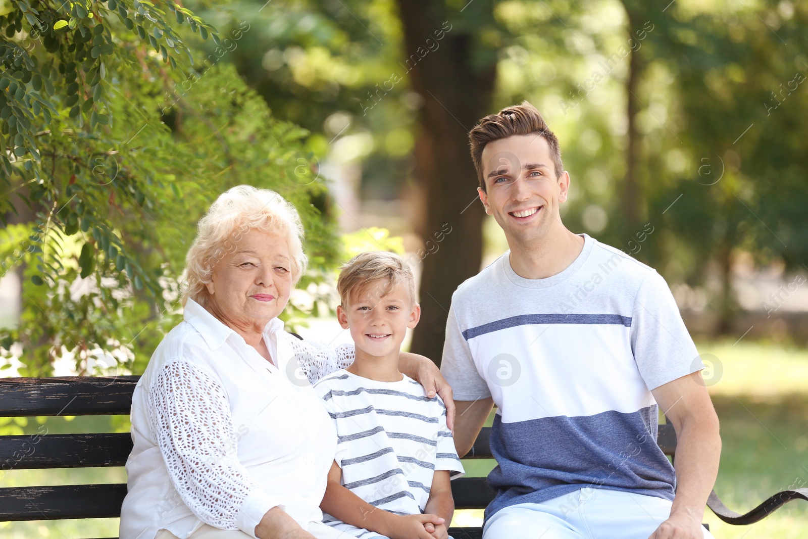 Photo of Man with son and elderly mother on bench in park