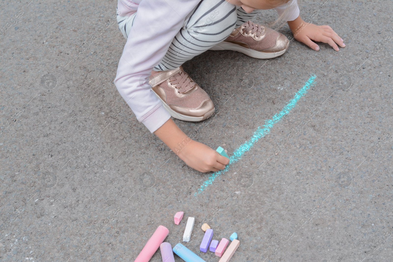 Photo of Little child drawing happy family with chalk on asphalt, closeup