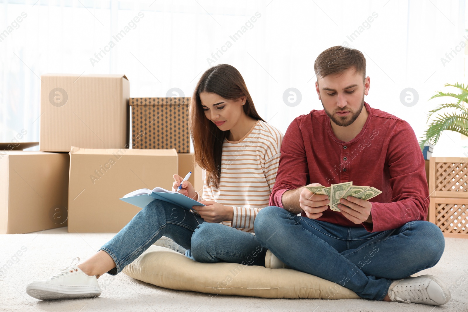 Photo of Unhappy young couple with money at home. Financial problems