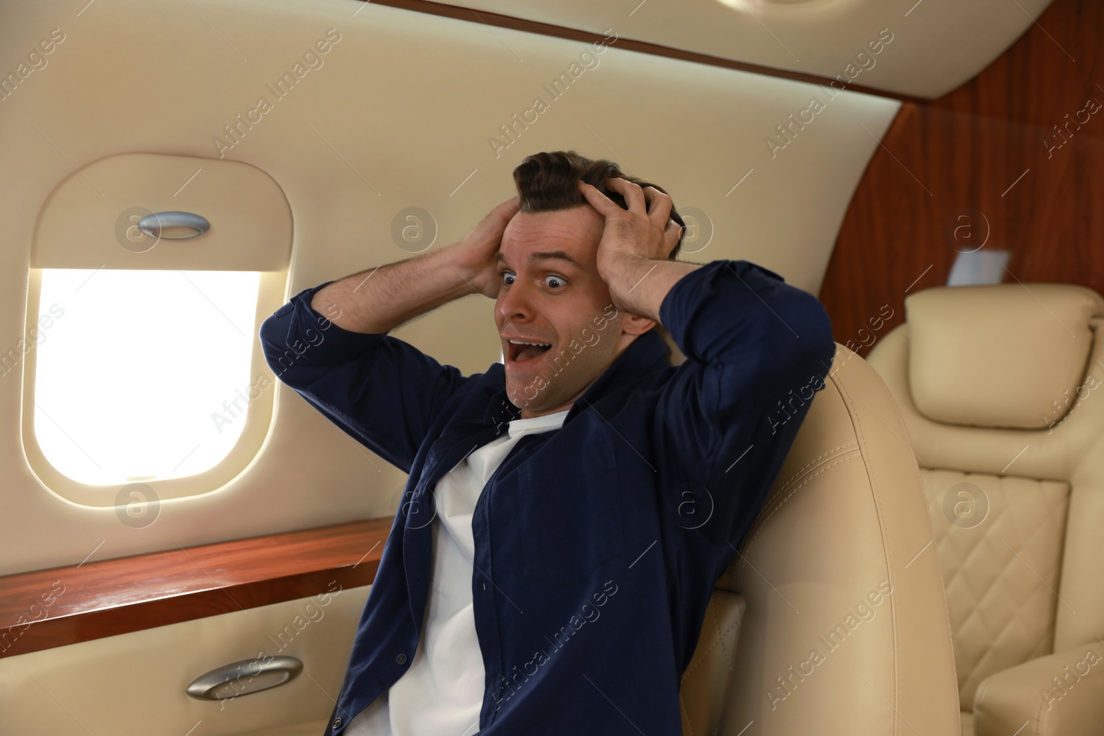 Photo of Scared young man suffering from aviophobia in airplane
