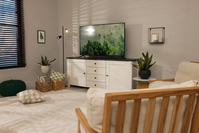 Photo of Cozy room interior with stylish furniture, decor elements and TV set