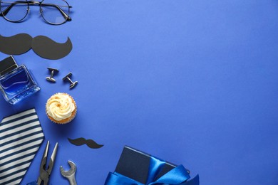 Photo of Father's day celebration. Delicious cupcake, paper mustache and men accessories on blue background, flat lay. Space for text