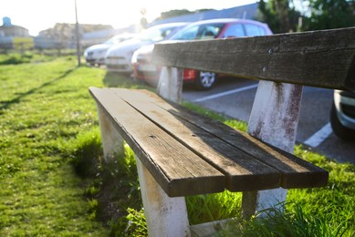 Wooden bench and green grass outdoors on sunny day