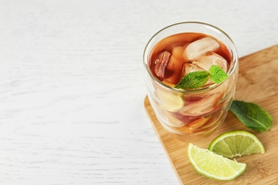 Glass of tasty ice tea with lime on white wooden table, above view. Space for text