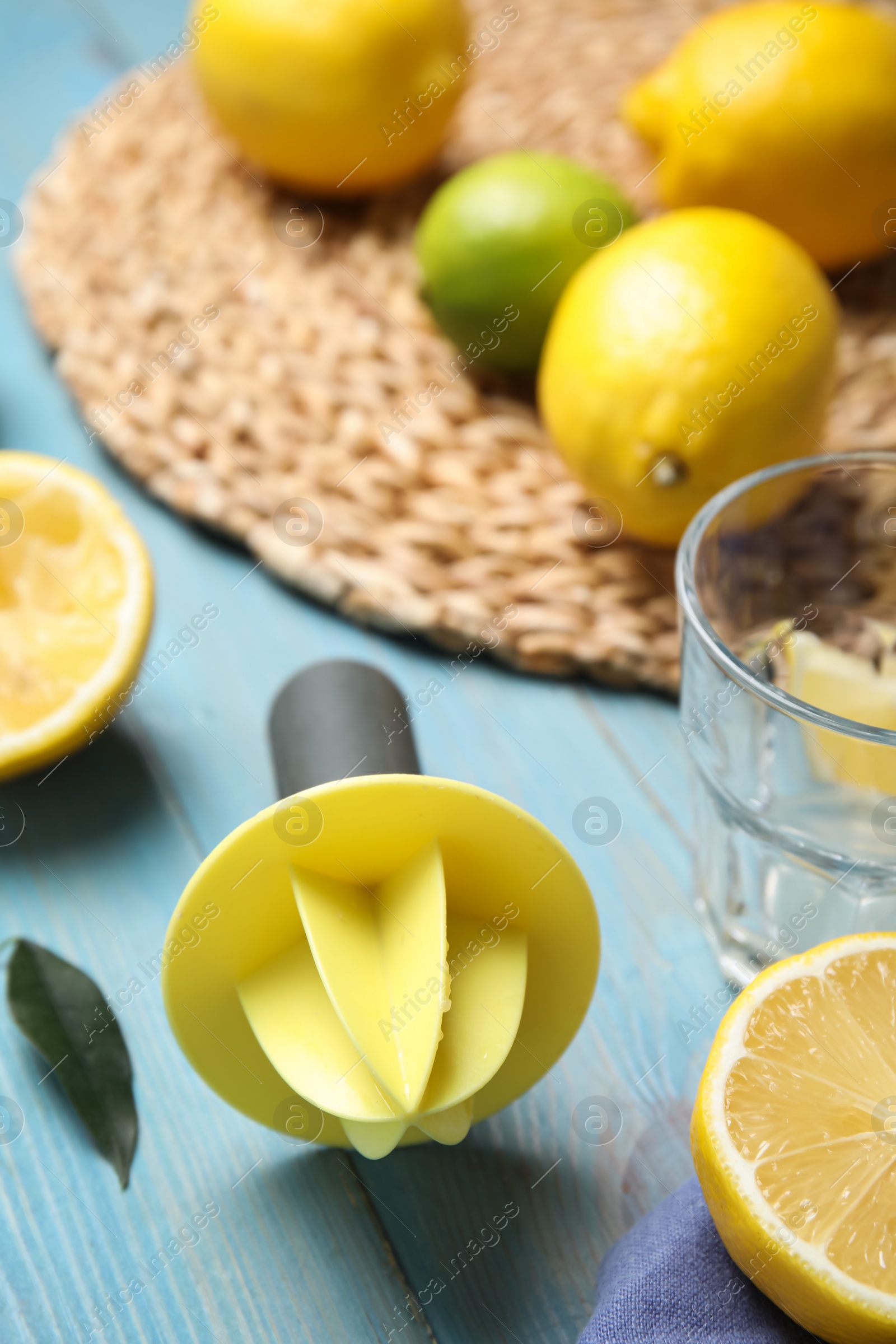 Photo of Citrus reamer and fresh lemons on light blue wooden table