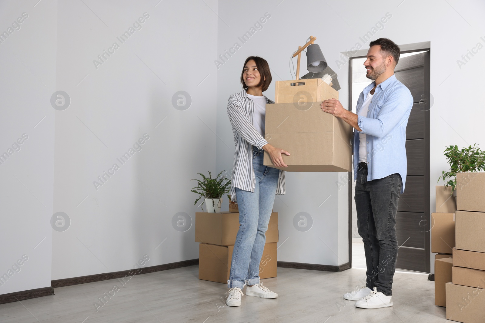 Photo of Happy couple with moving boxes entering in new apartment