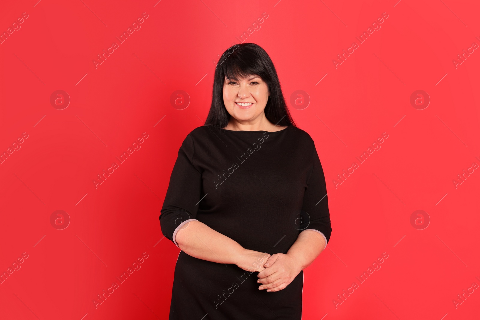 Photo of Beautiful overweight mature woman with charming smile on red background