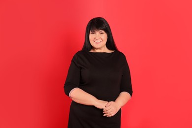 Beautiful overweight mature woman with charming smile on red background
