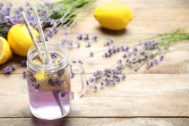 Photo of Fresh delicious lemonade with lavender in masson jar on wooden table. Space for text
