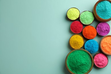 Colorful powders in bowls on light background, flat lay with space for text. Holi festival celebration
