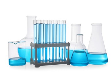 Photo of Different laboratory glassware with light blue liquid on white background