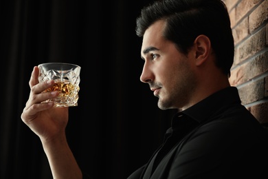 Photo of Young man with glass of whiskey indoors