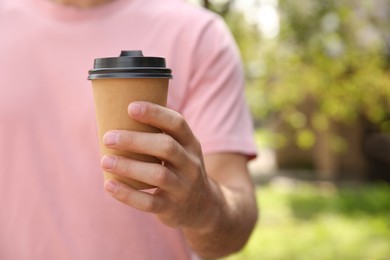 Photo of Man with takeaway coffee cup on city street, closeup. Space for text