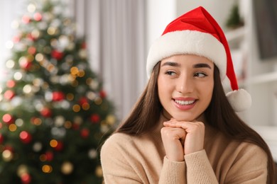 Photo of Smiling woman wearing red Christmas hat indoors. Space for text