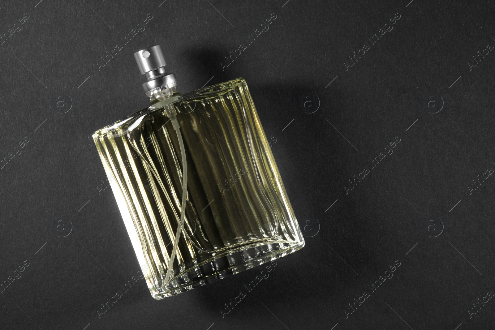 Photo of Luxury men`s perfume in bottle on black background, top view. Space for text