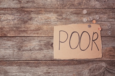 Photo of Carton sign with word POOR and space for text on wooden background, top view